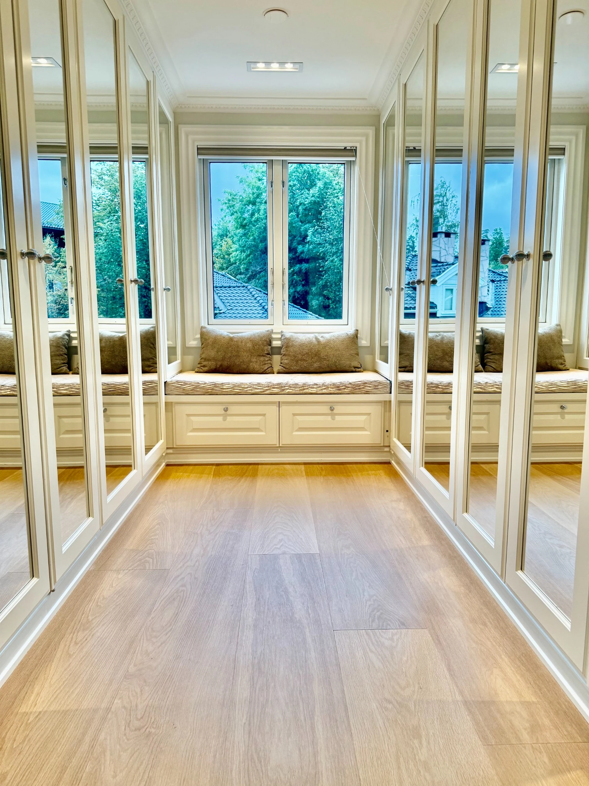 Walk-in closet with mirrored wardrobes and window seat